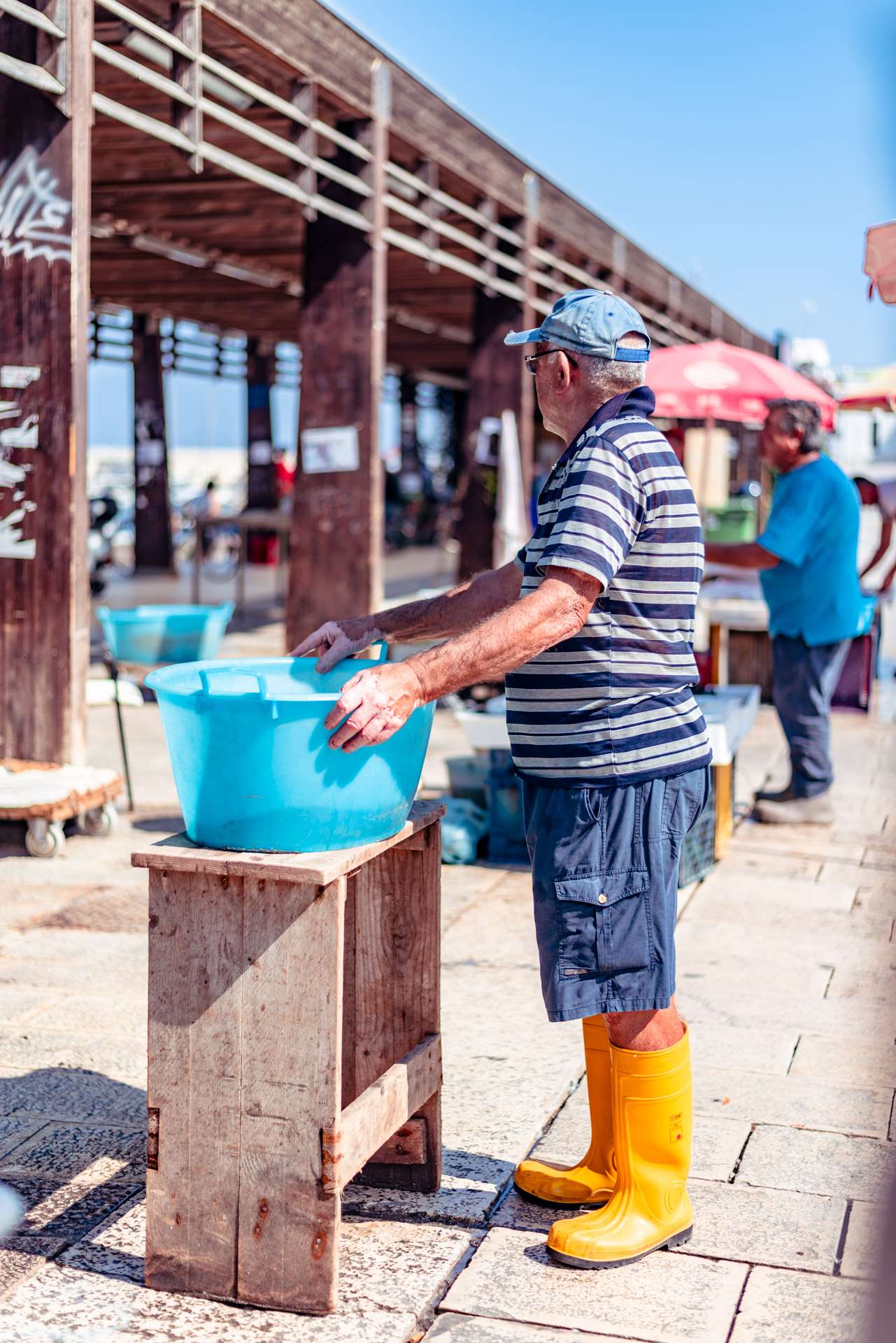 Fisherman with yellow boots at the fish market at the jetty Saint Nicholas in Bari