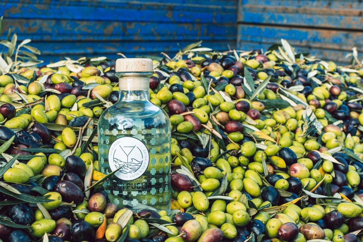 a bottle of gin di puglia with a lot of olives