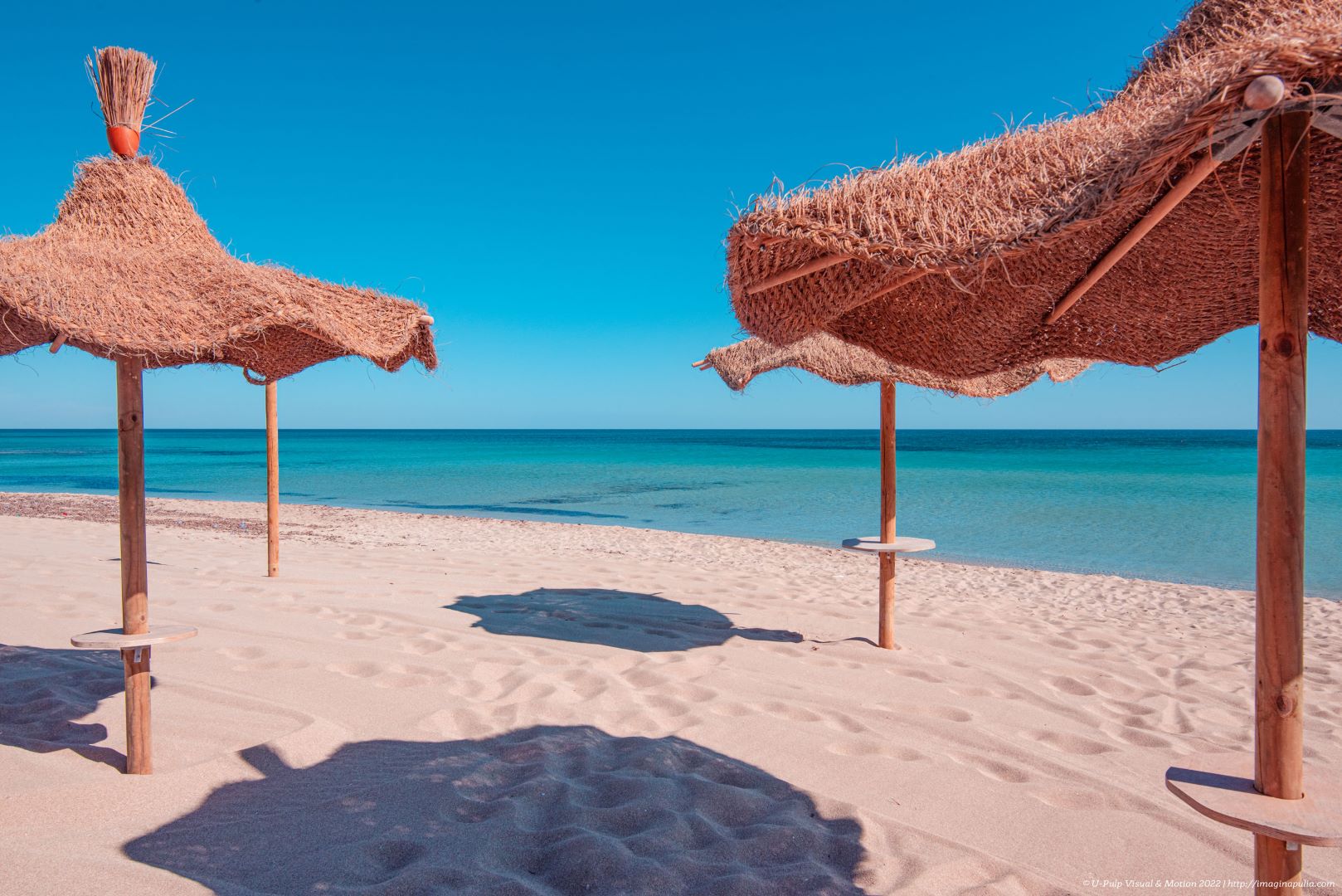 ombrelloni di paglia sulla spiaggia caraibica di campomarino di maruggio in provincia di taranto salento puglia